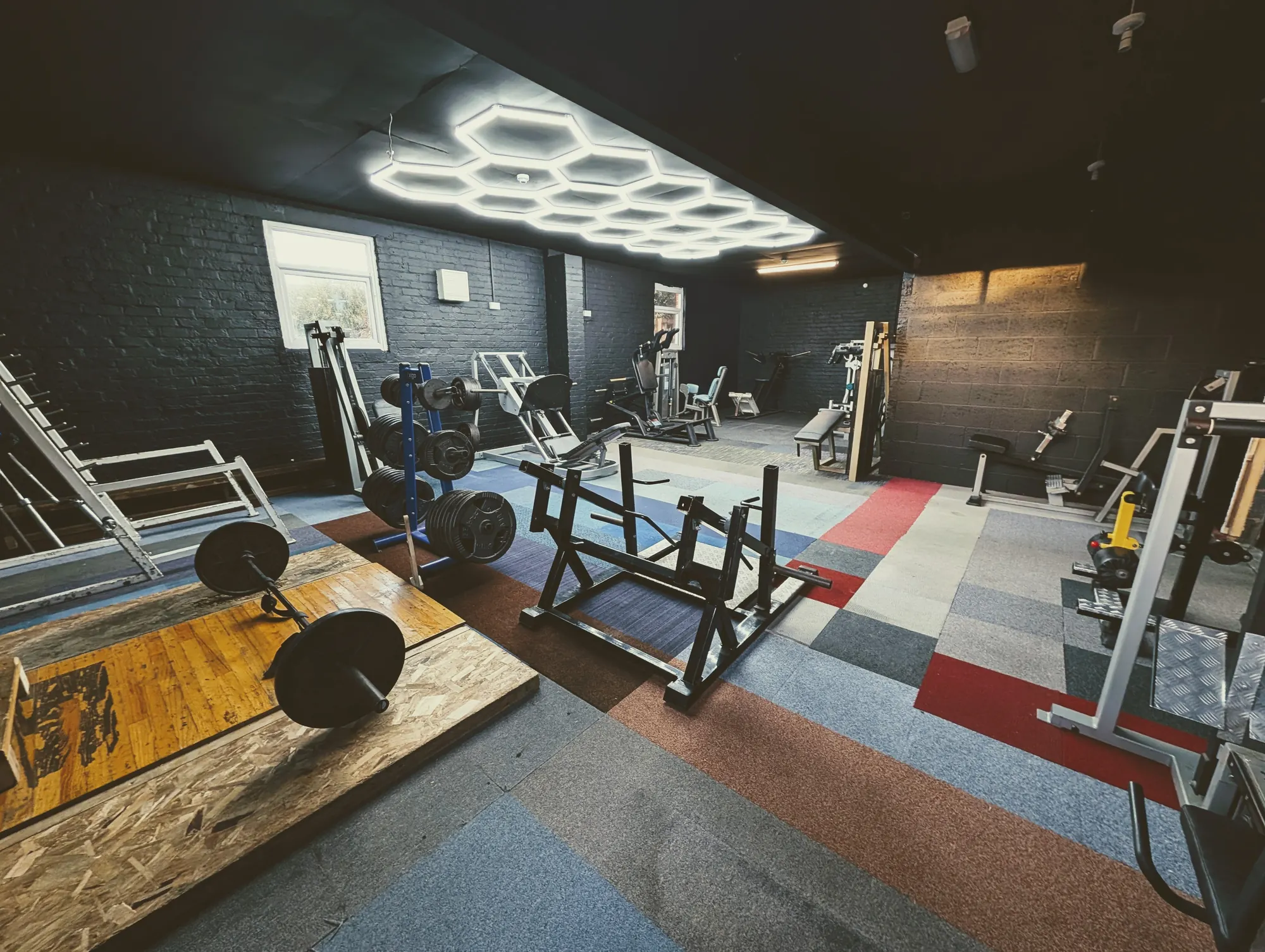 Hexagon-lit training room with racks, benches and lifting platforms at THE GYM Rhyl